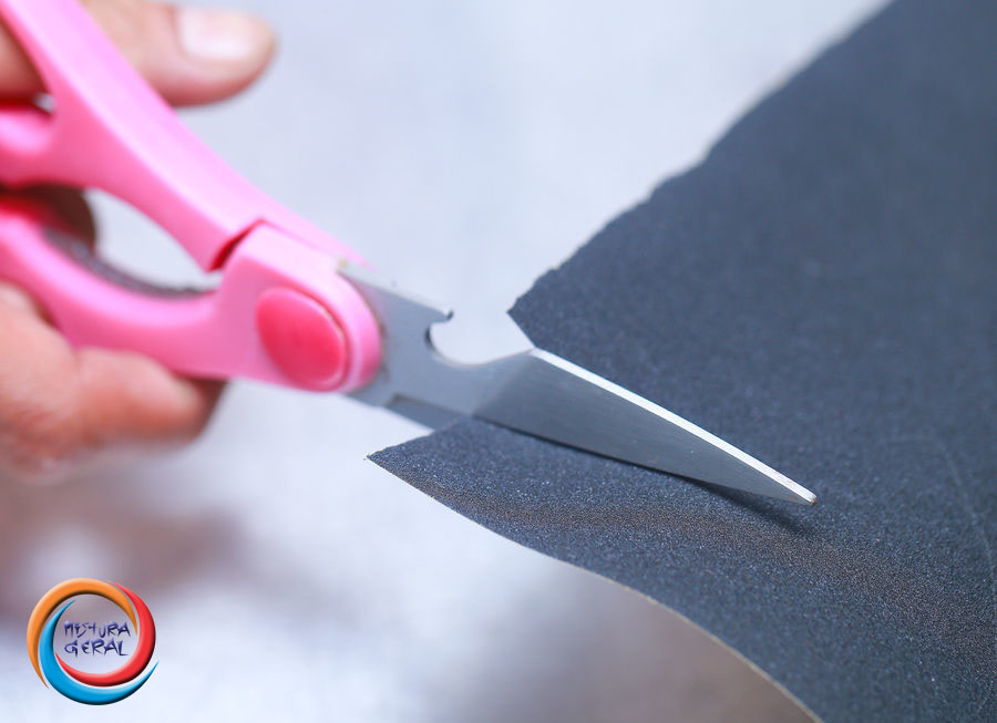 Amole tesouras cortando uma folha de lixa de papel.